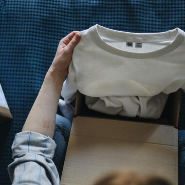 Close-up of hands opening a package containing a new white t-shirt indoors.