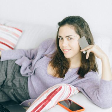 Relaxed woman using smartphone and laptop for online shopping at home.
